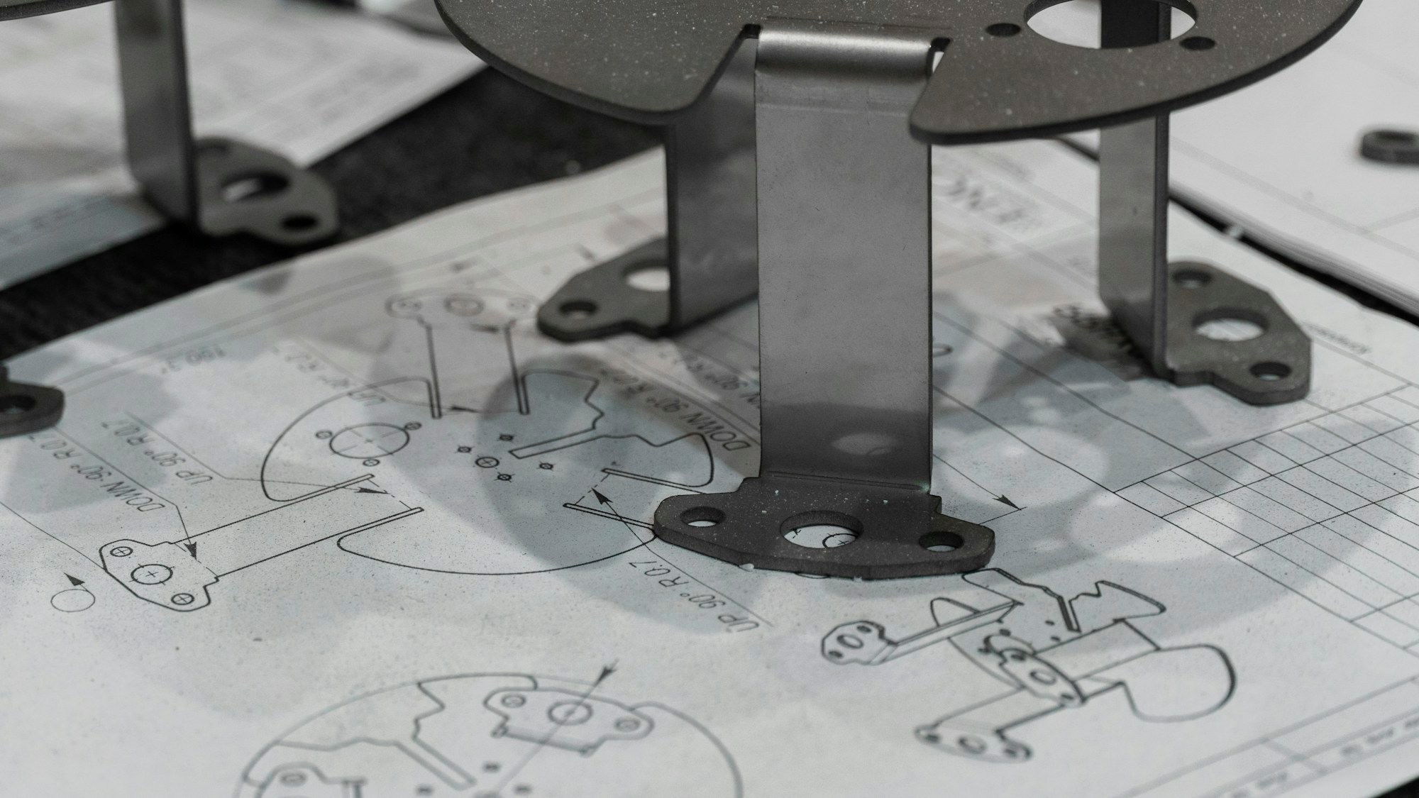Manufactured metal parts placed on engineering drawings.