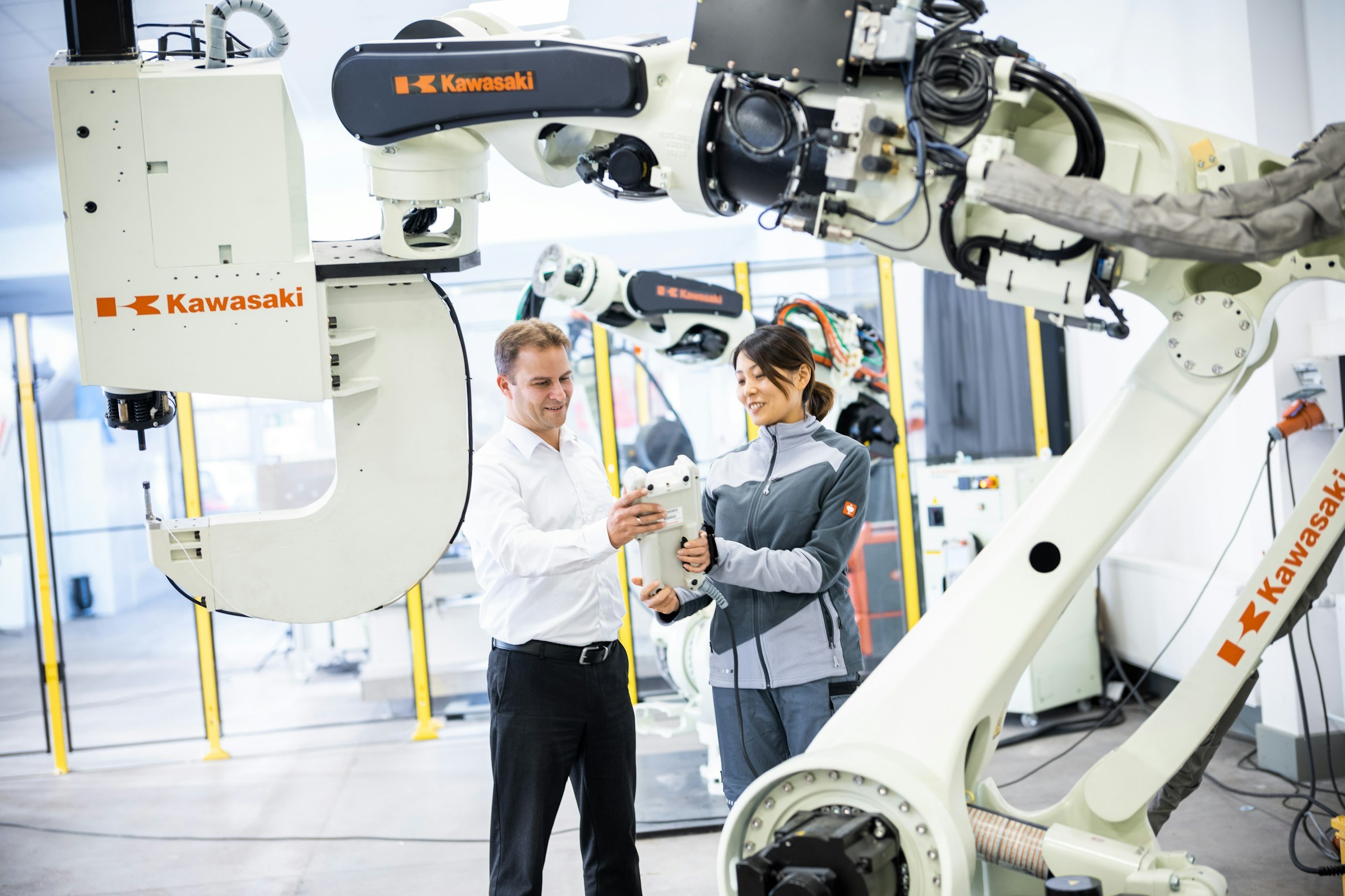 Two engineers checking an industrial robot arm.